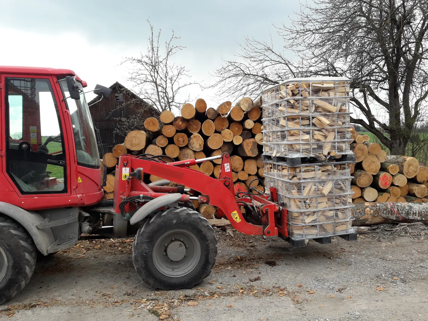 Brennholz in Lagerboxen wird am Standort mit dem Radlader bewegt